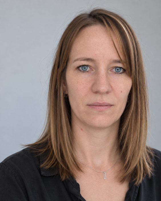 Portrait de Melanie Vogtli, de face, sur un mur gris clair.